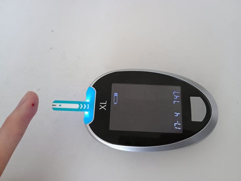 Setetes darah di ujung jari di samping glukometer yang sudah terpasang strip tes