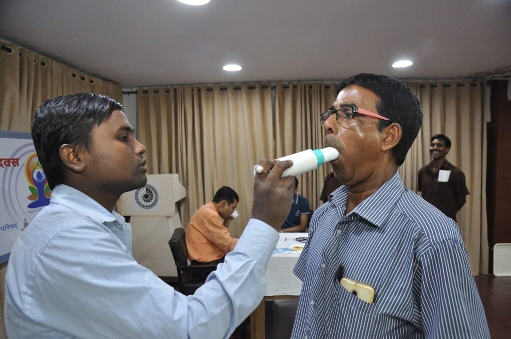 Seorang peserta pemeriksaan kesehatan meniup alat spirometri dengan didampingi petugas