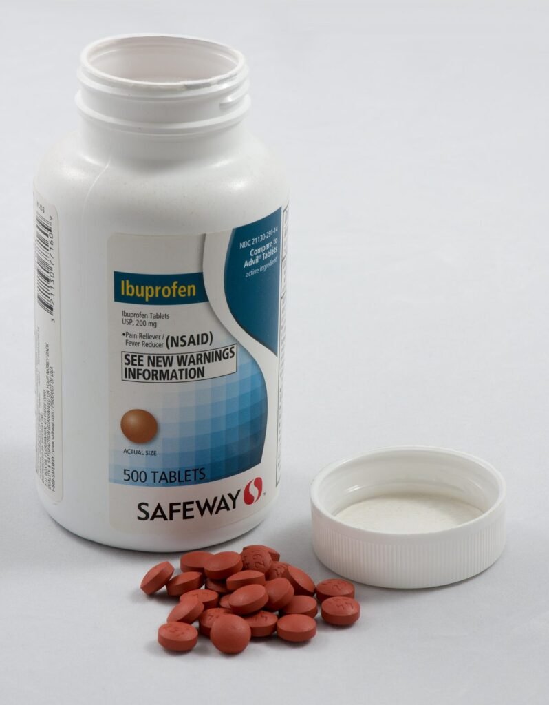 Botol obat antinyeri dengan tablet di depannya